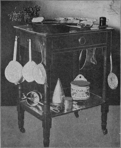 A Two Story Kitchen Table On Rollers Made from an Old Fashioned Wash Stand with Zinc Covered Top and Hooks for Utensils.