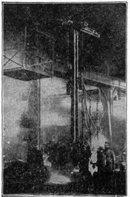Fig. 188.   Ramming Molds   the First Step in Molding a Cast Iron Pipe. A large cast iron flask is placed in a pit and a pattern is placed in the flask. Sand is then filled in around the flask and rammed down hard. In this case, the rammers are driven by compressed air and are suspended by a stationary overhead crane. The pattern is then drawn and the mold is ready for the core,