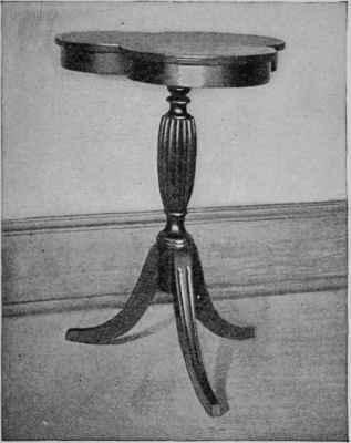 A clover leaf top. a reeded column, and fluted legs are the features of this little table.