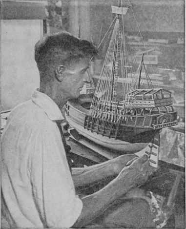 Captain McCann putting the finishing touches on the hull of his own exhibition model of the ship, which is half as large again as that in the accompanying drawings.