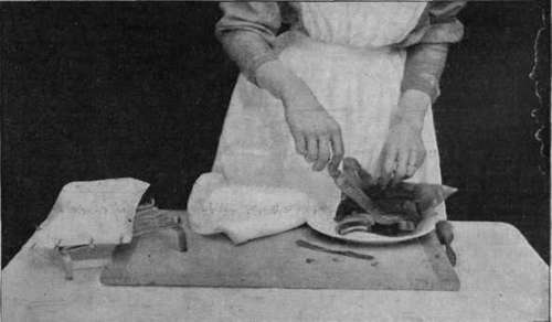 Removing the cooked chop and tomato from the bag. On the left is shown the bag containing the chop ready for the oven. Note the manner in which this is closed by paper fasteners