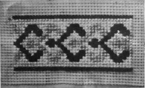 A design for a border to be used on a dress. It can be worked upon the material, the threads of the canvas being removed carefully shades, including terra cotta, indigo, light green, deep brown, white, and pale gold, silky embroidery threads being employed.