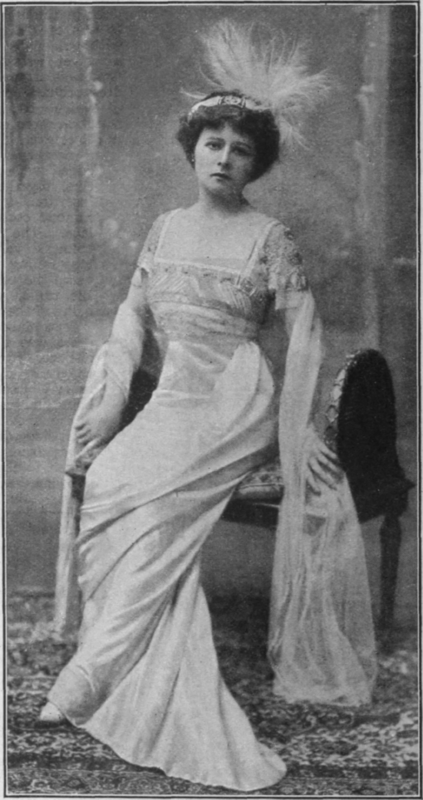 An evening frock of ivory white satin, with diamond and ruby corsage trimming, worn by Miss Mabel Love in  98.9,  A giant pink osprey formed the head dress worn with the costume Dover Street Studios
