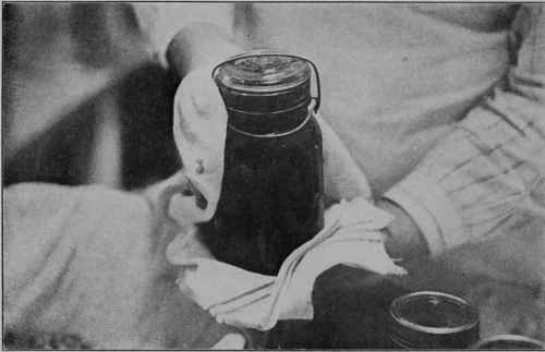 Fig. 7 - After being processed or sterilized for the required length of time, the jars are removed and the covers immediately tightened.