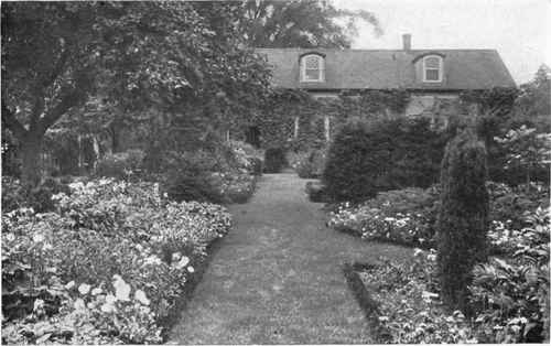 Fig. 127.   Turf walks are preferable for gardens. The greensward forms a canvas of pleasing color upon which to arrange the contrasting units of flowering plants.   See page 155.