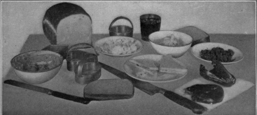 Fig. 30.   Everything is ready for making sandwiches. Notice the soft butter in the bowl at the right. There is a plate of plain cheese, and a bowl of cheese mixed with chopped nuts and chopped peppers.