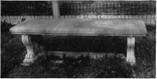 Concrete lawn bench with considerable ornament.