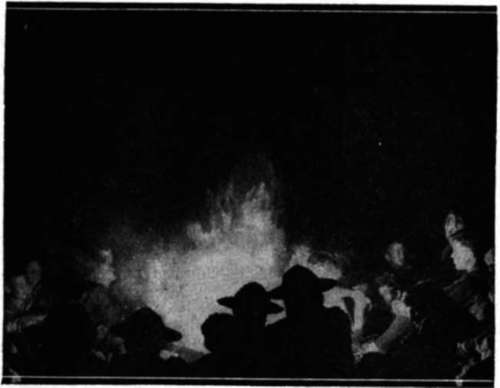 At the camp fire a warm glow over everything the smoke rising into the darkness