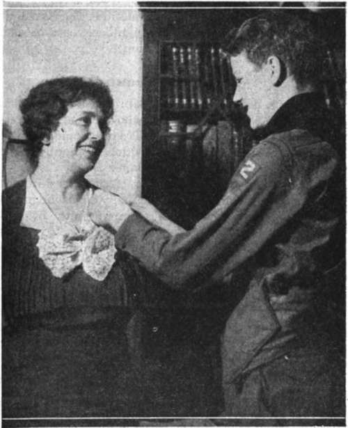 Eagle Scout is pinning a miniature of his Badge of Rank on his Mother